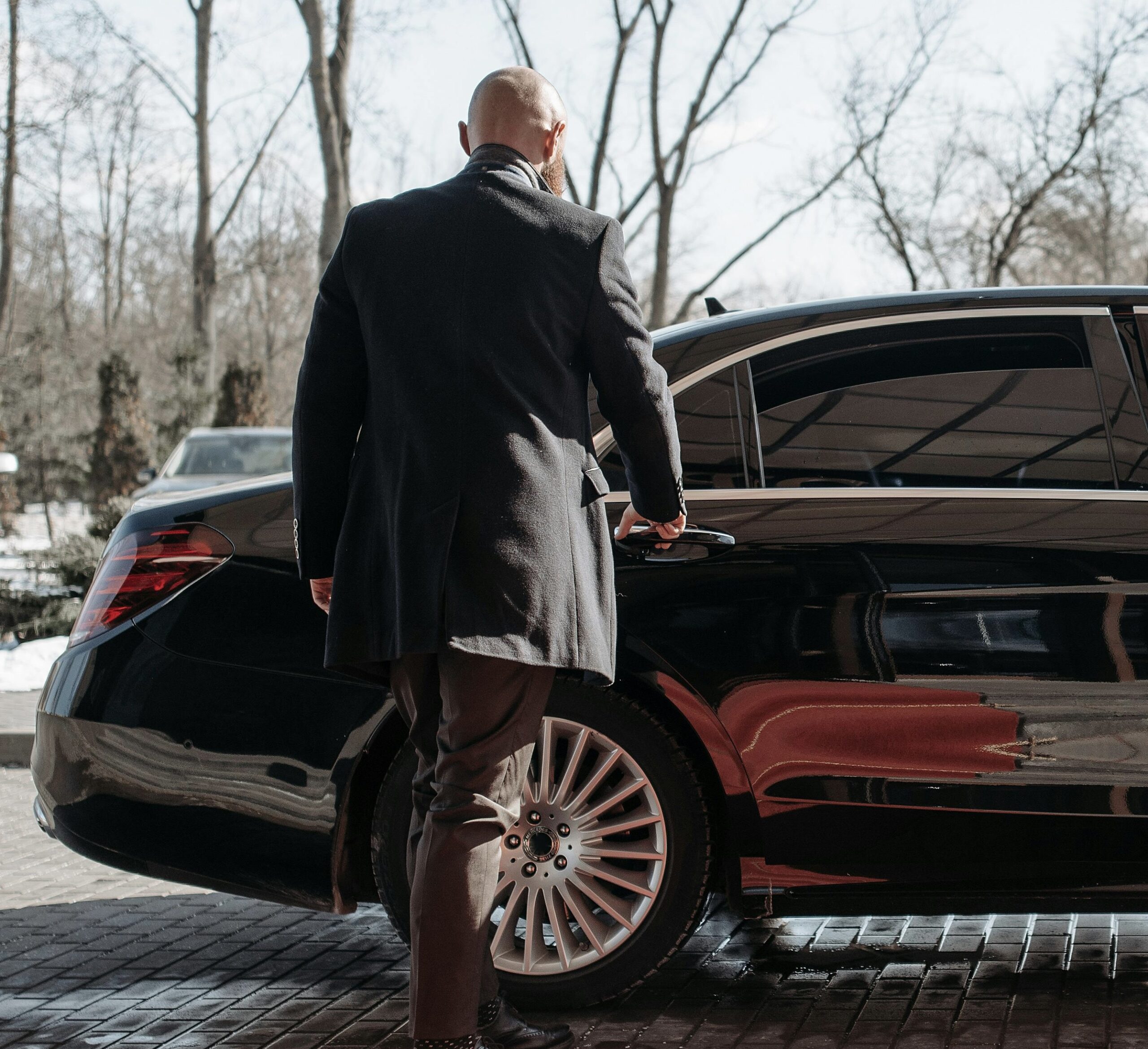 Private chauffeur opening car door for UHNW family in a luxury UK setting